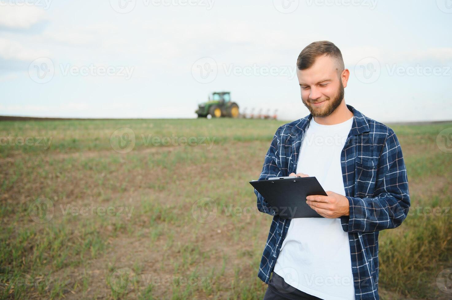lantbruk. jordbrukare arbetssätt i en fält i de bakgrund traktor plogar jord i en fält av vete. jordbruk lantbruk begrepp. företag jordbrukare i de fält foto