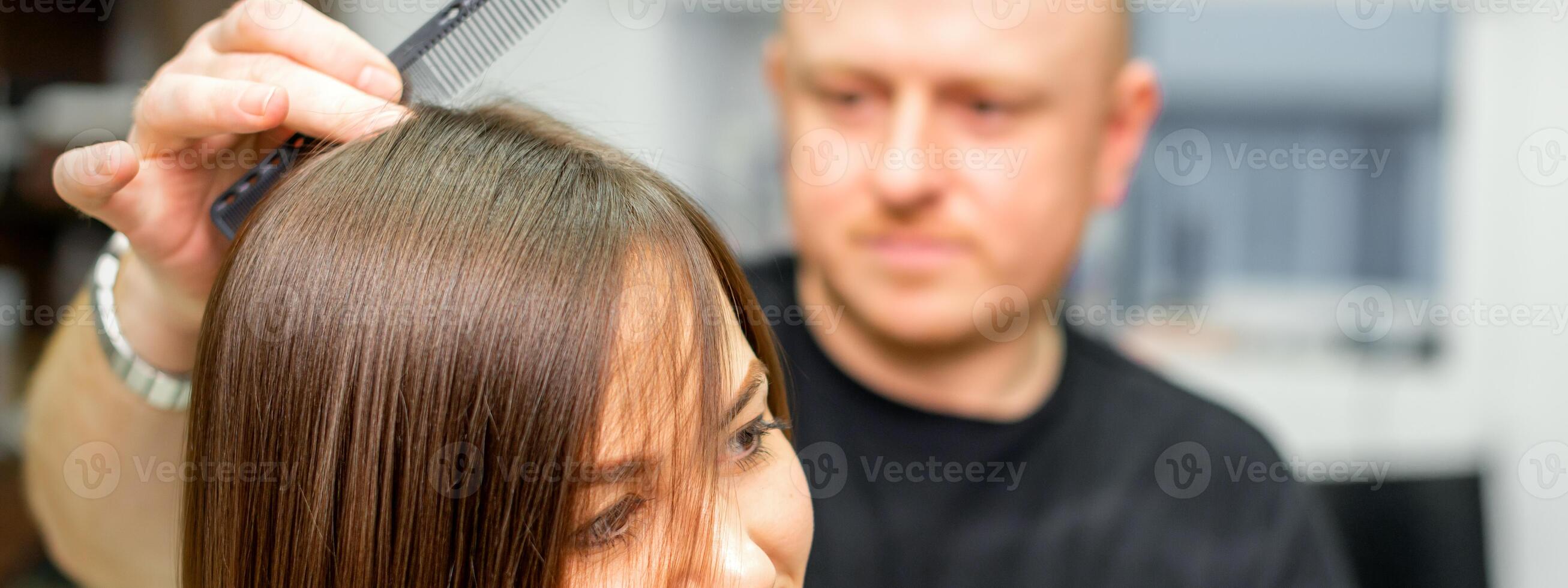 ung caucasian brunett kvinna har henne hårstyling förbi en manlig frisör på en salong. foto