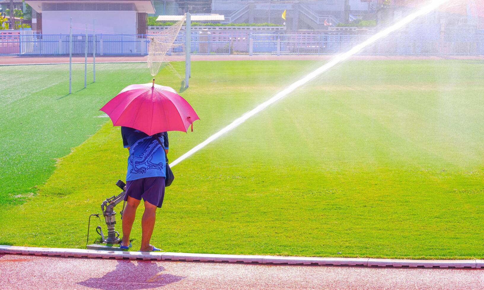 arbetstagare använder sig av stor pistol hög tryck sprinkler till vattning gräs fält i stor fotboll stadion foto