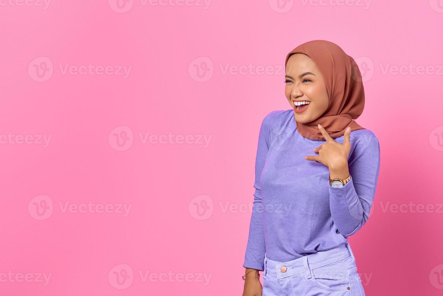 porträtt av glad ung asiatisk kvinna tittar åt sidan på rosa bakgrund foto