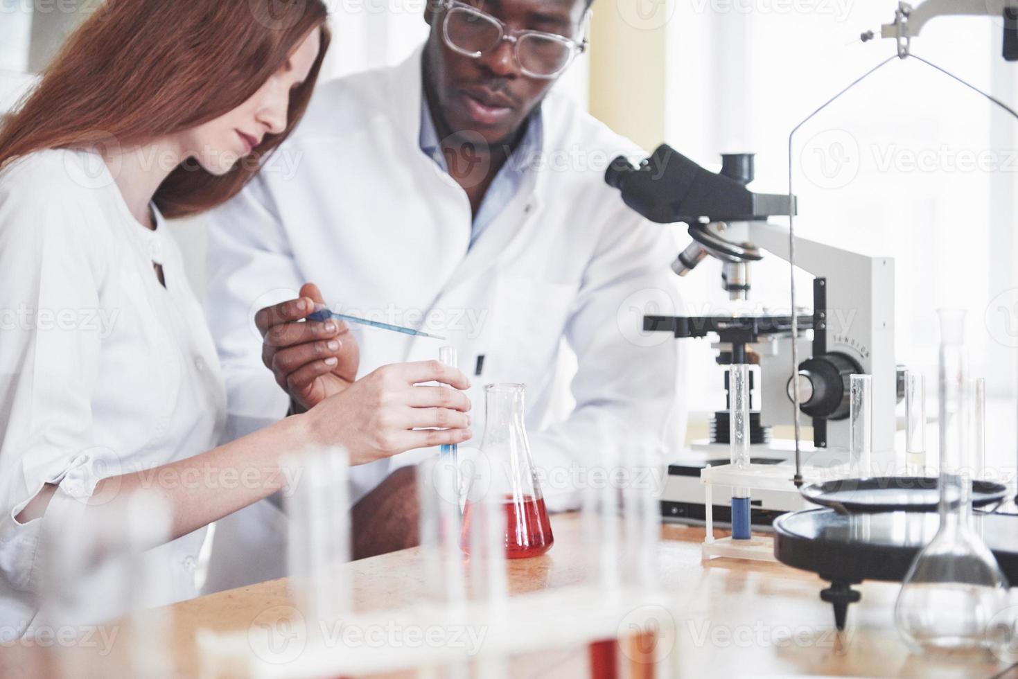 forskare arbetar nära med mikroskopet i laboratoriet genom att utföra experiment och analyser. foto