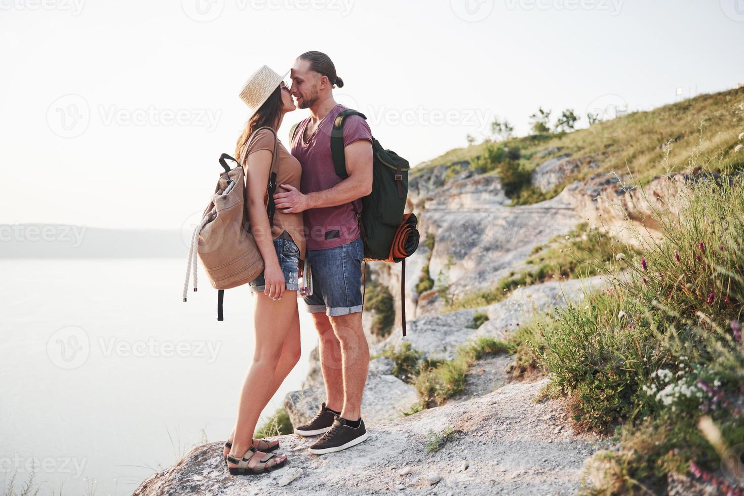två turistmanar och -kvinna med ryggsäckar står på toppen av berget och njuter av soluppgången. resa livsstil äventyr semester koncept foto