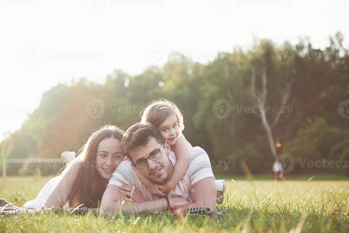 lycklig familj, far till mor och dotter till baby i naturen vid solnedgången foto