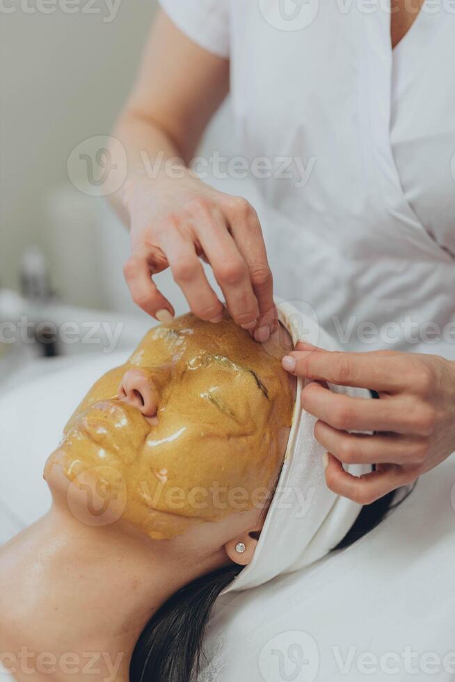 en flicka på en kosmetolog gör kosmetisk förfaranden. alginat mask foto