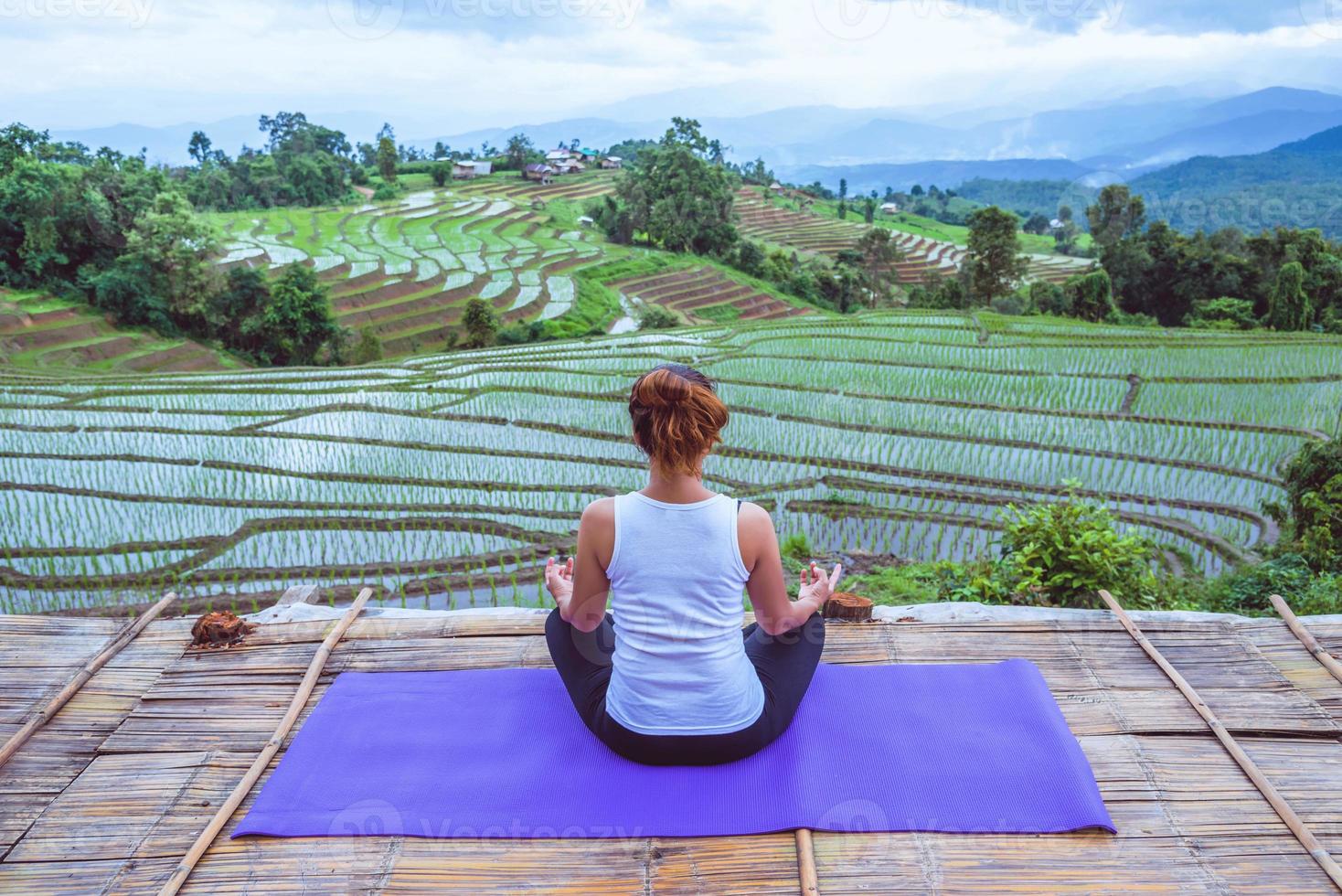 asiatisk kvinna koppla av i semestern. spela om yoga. på balkongen landskap naturfält foto