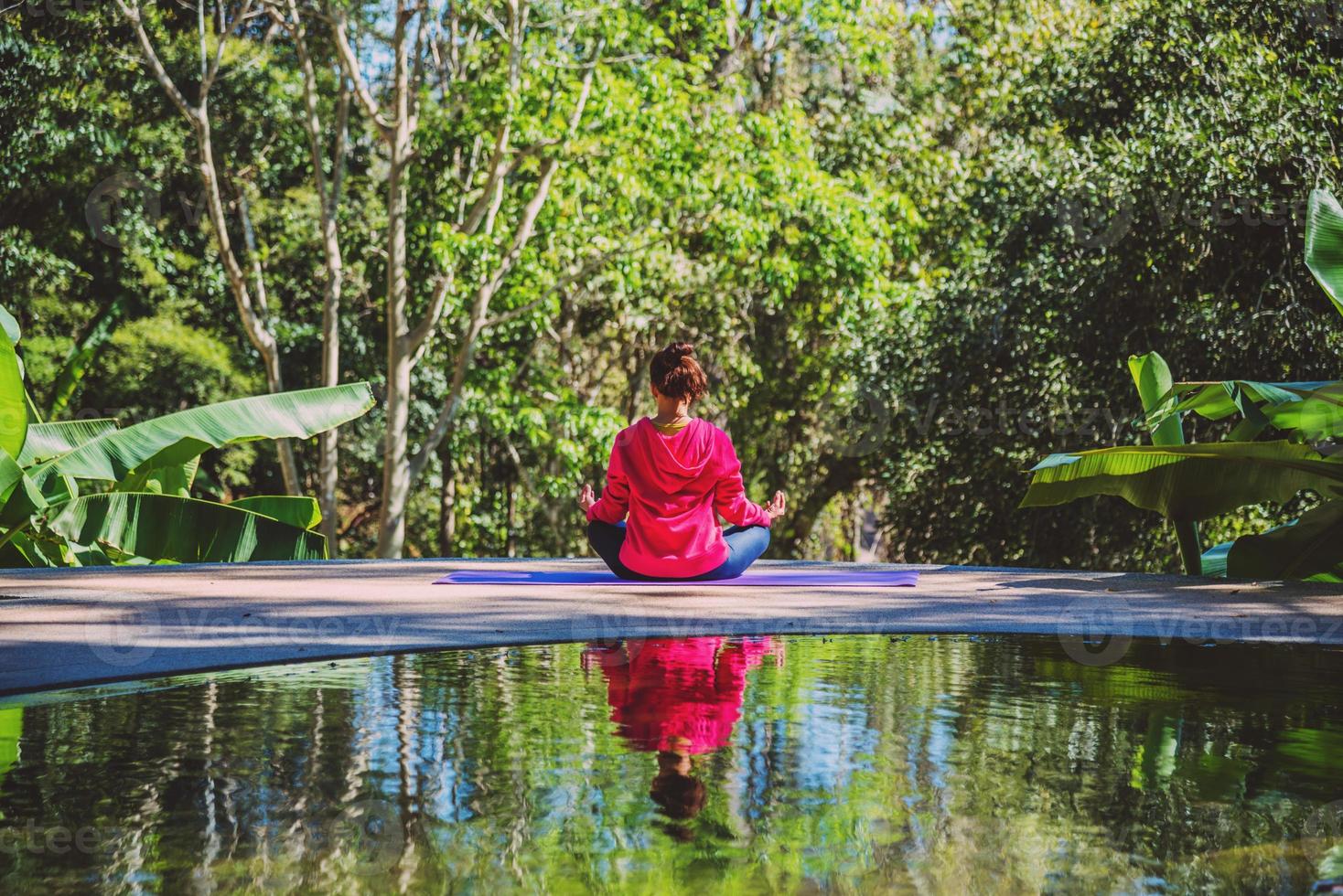 ung kvinna reser naturen hon stående träning vid poolen avkopplande, reflektioner av asiatisk kvinna på vattenytan. foto