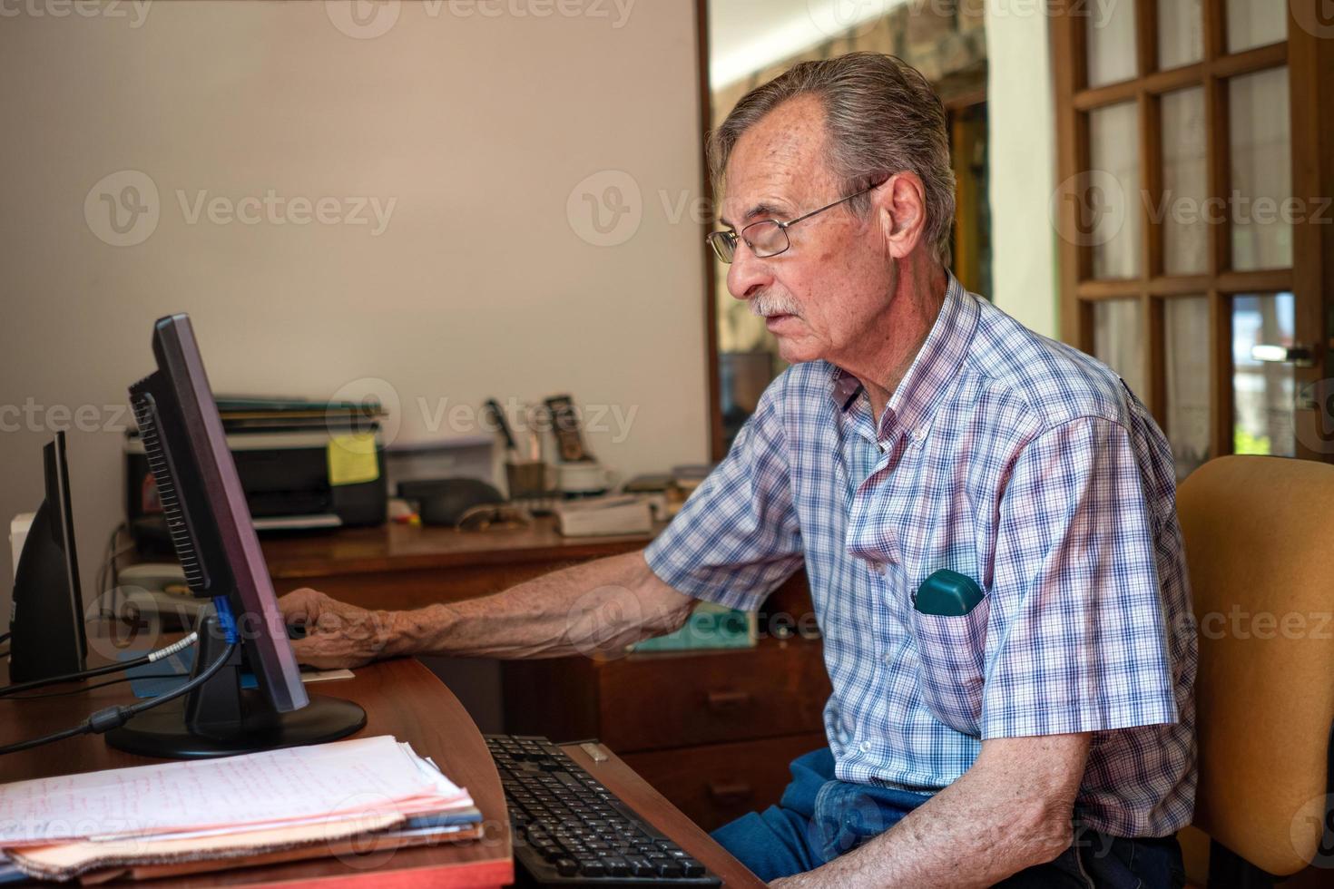äldre man mycket koncentrerad framför datorn hemma, foto