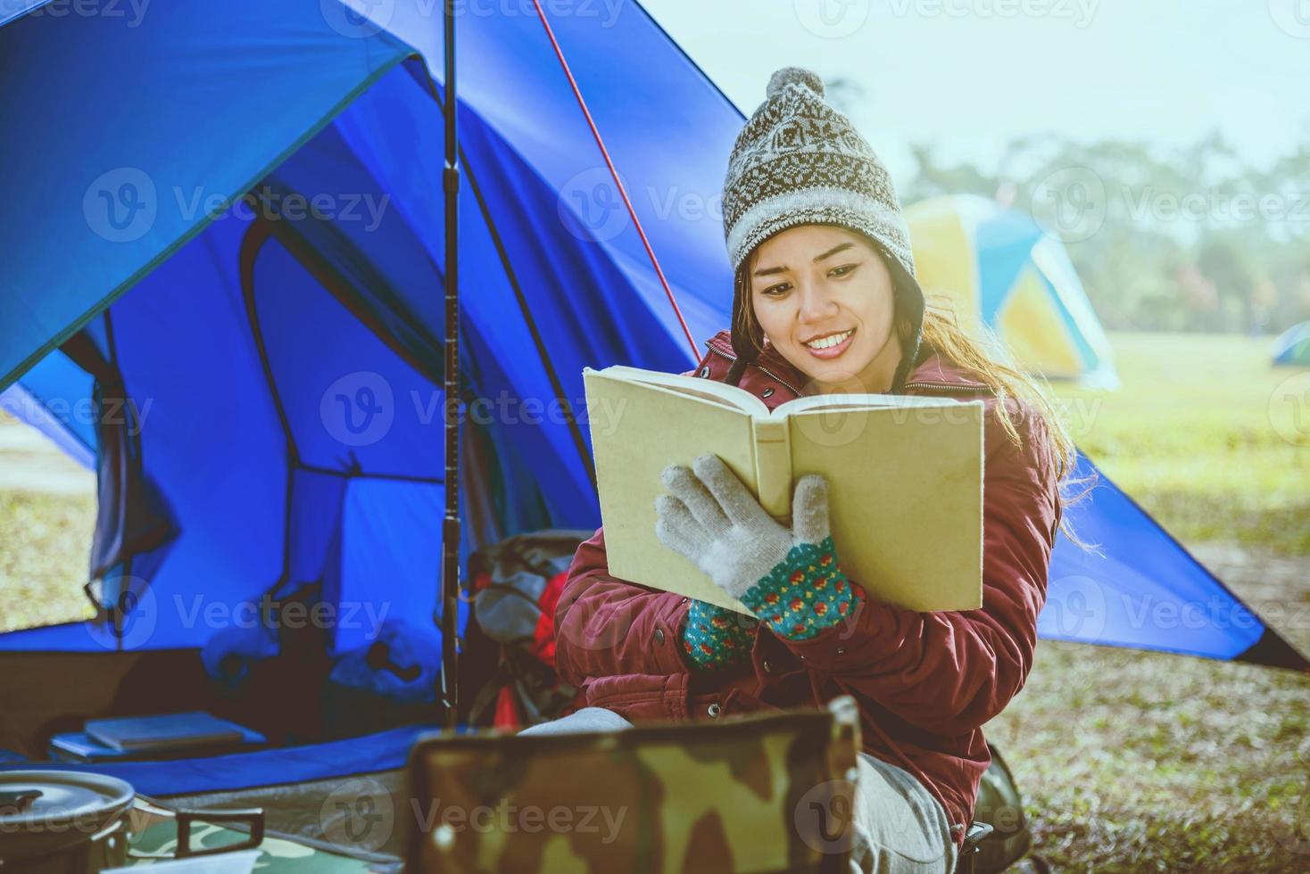 asiatiska kvinnor reser koppla av camping i semestern. camping på berget. sitta slappna av läsa en bok i stolen. thailand foto