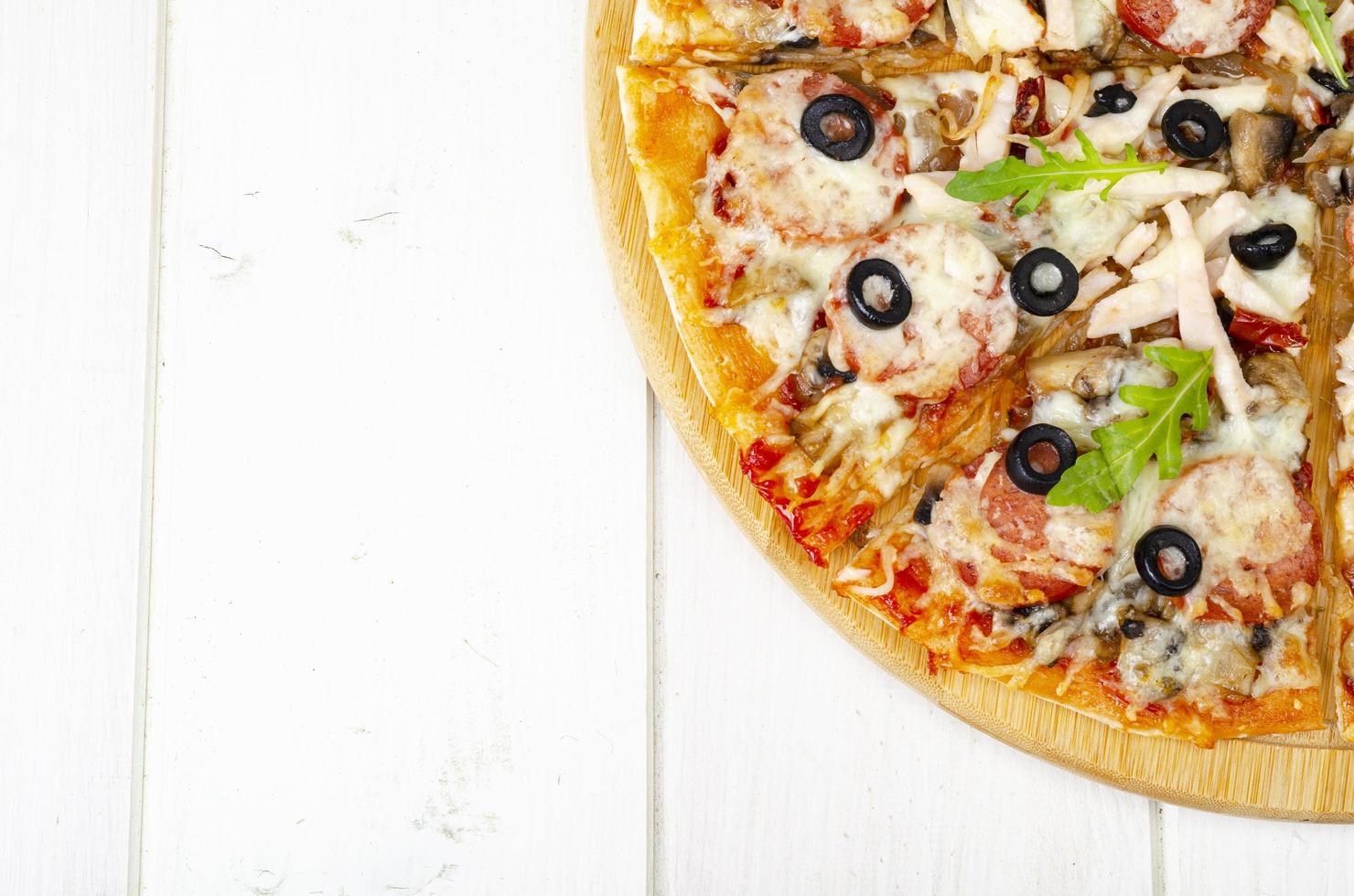 hemlagad pizza med salami, skinka och mozzarella på träbord. studiofoto foto