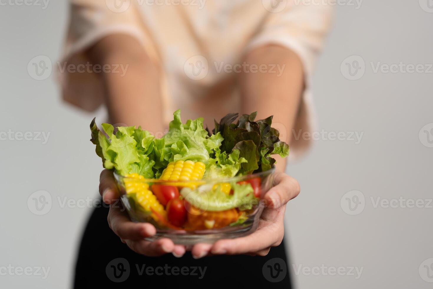porträtt av en Lycklig lekfull asiatisk flicka äter färsk sallad från en glas skål efter träna på Hem. ung lady njuter friska näring och organisk mat, har vegetarian måltid foto