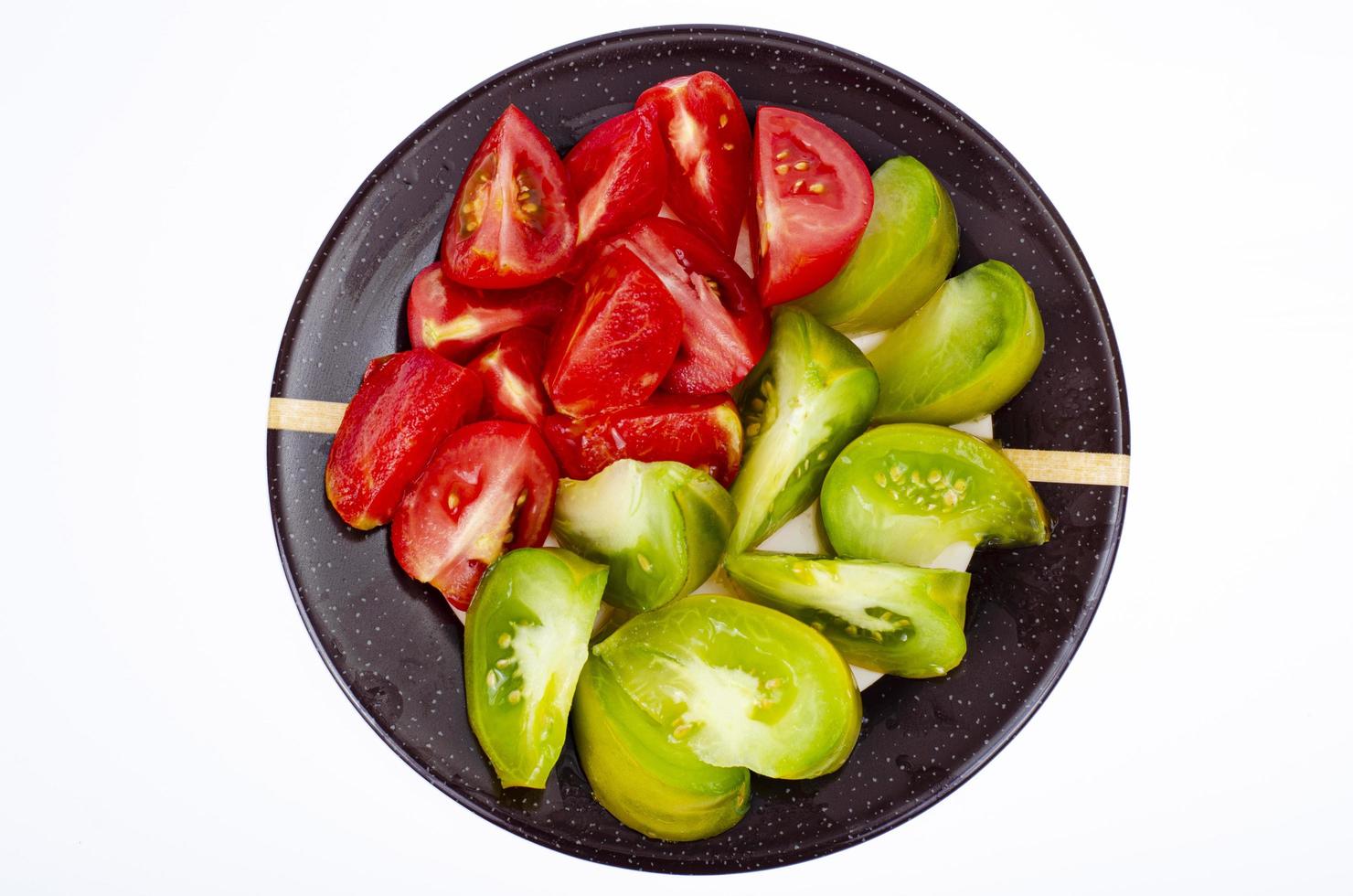 tallrik med skivor av mogna tomater i olika färger. studiofoto. foto