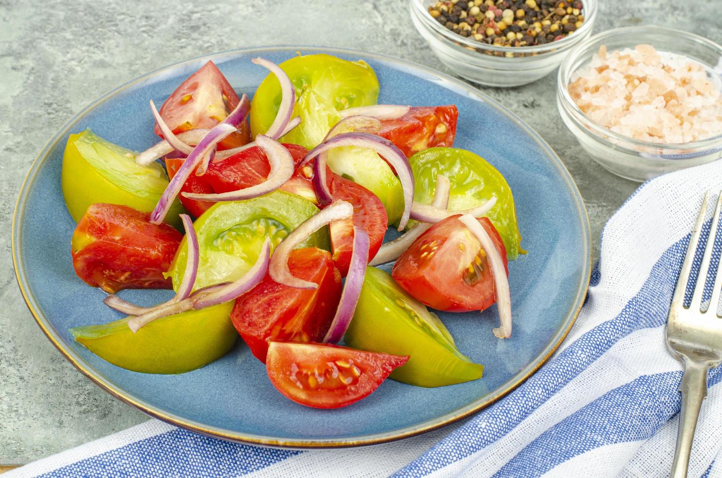 dietmat. sallad av skivor av färska ljusa tomater och lök. studiofoto foto