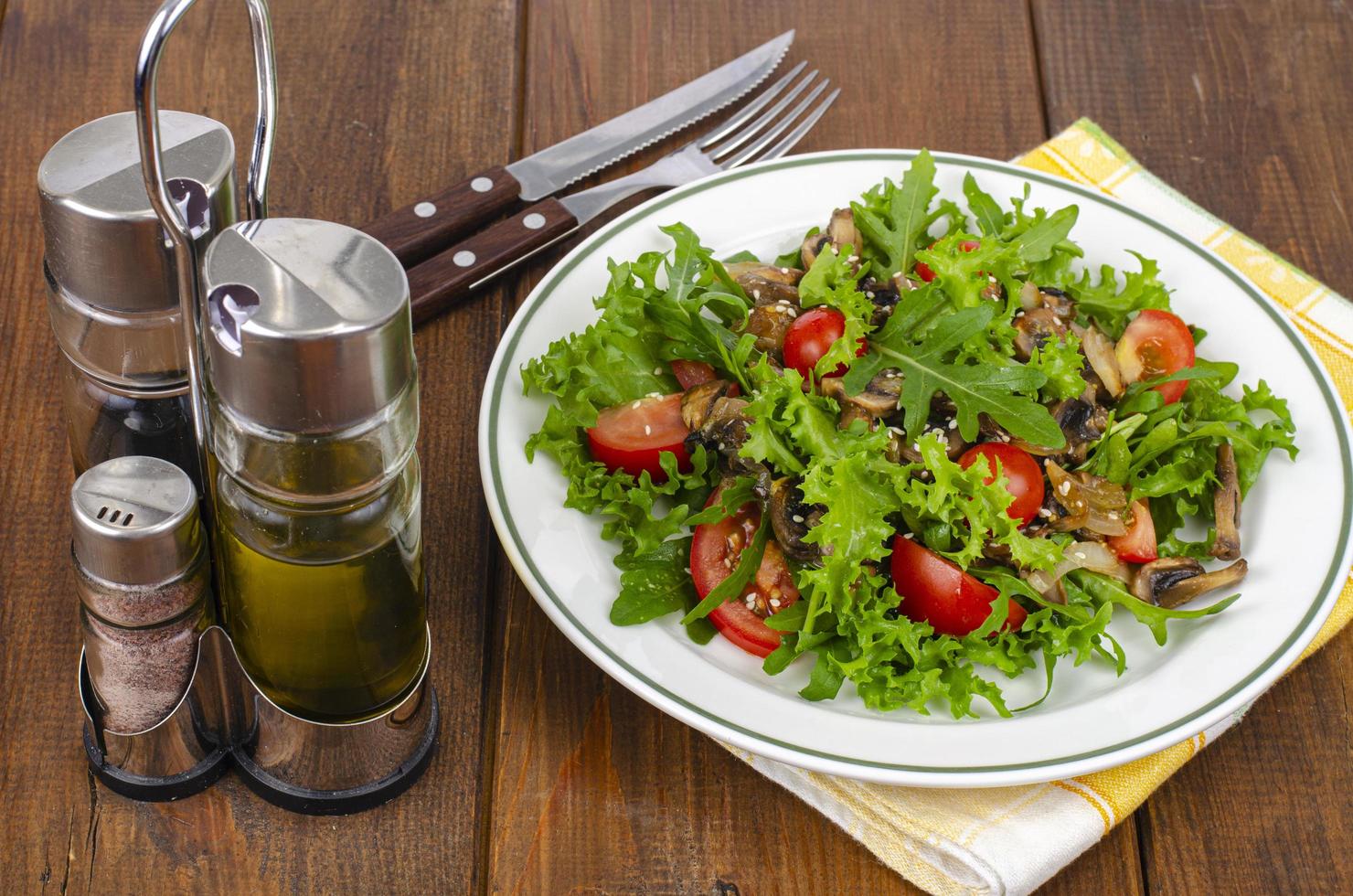 dietsallad av ruccolablad, tomater och stekt svamp på träbord. studiofoto foto