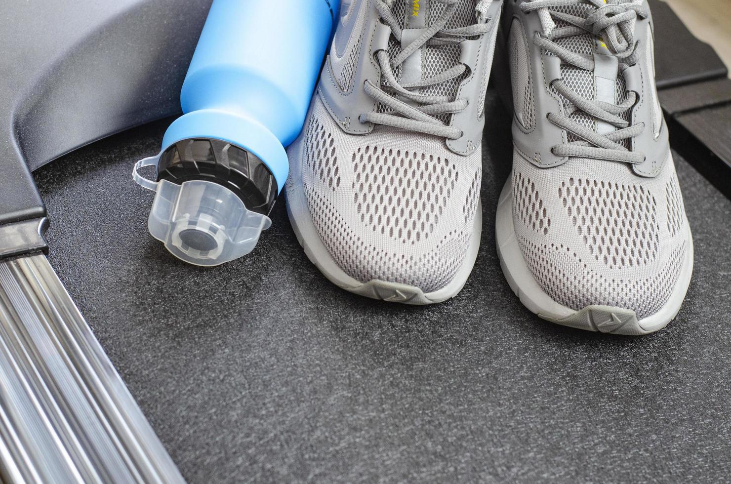 löparbana med sneakers och flaska vatten på svart bakgrund. träningsredskap för hälsan. studiofoto foto