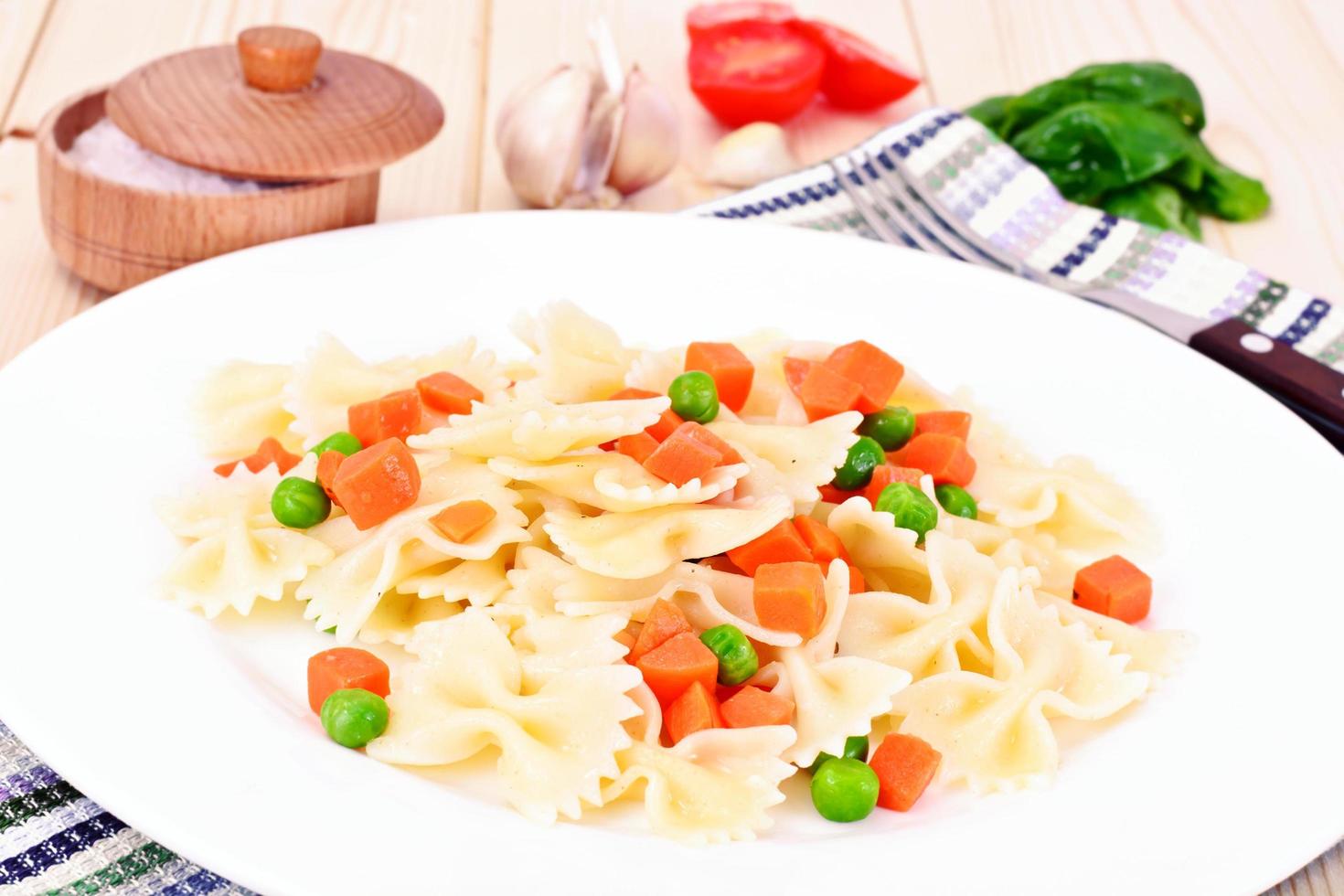 pastabåge med tärnade morötter, salami och gröna ärtor foto