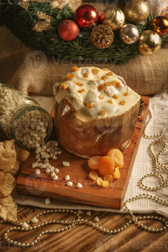 vit choklad panettone med torkad aprikos på träbord med juldekorationer foto