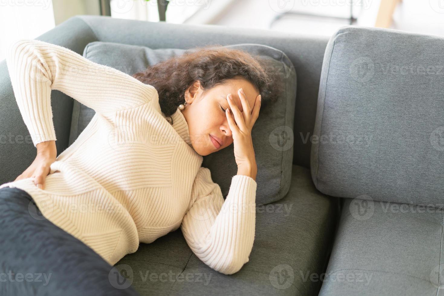 latinsk kvinna liggande på soffan med känsla av ryggvärk foto