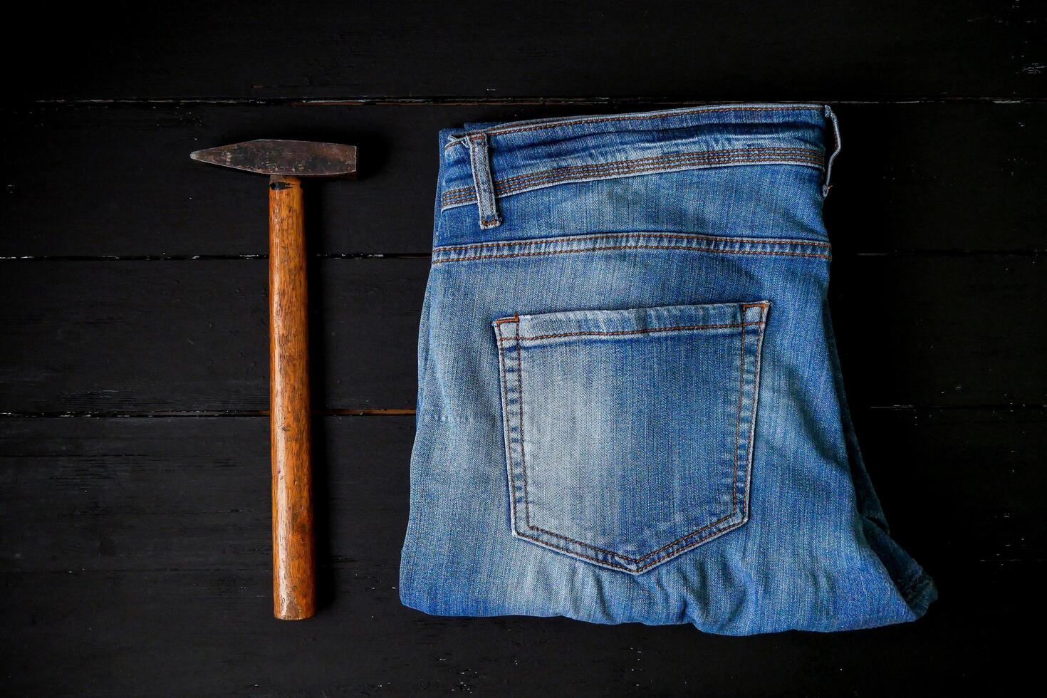 en par av jeans och en hammare på en svart bakgrund foto