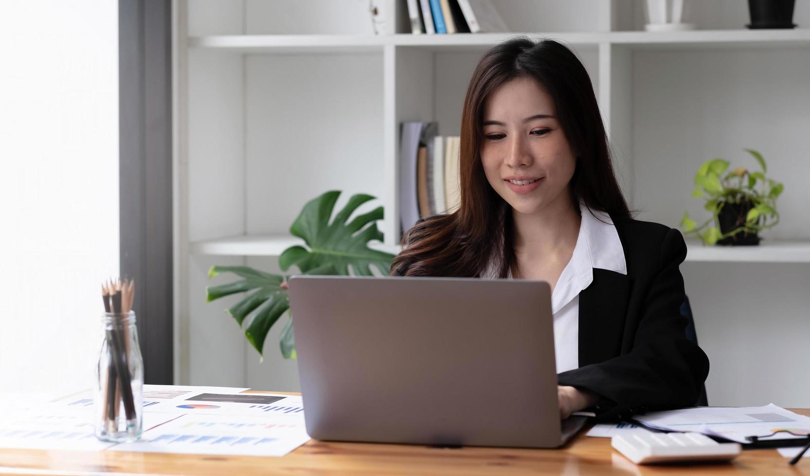 asiatisk affärskvinna som använder bärbar dator för att göra matematikfinansiering på träskrivbord på kontoret, skatt, redovisning, finansiellt koncept foto