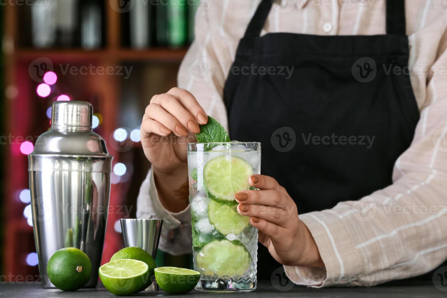 kvinnlig bartender som gör färsk mojito på bordet i baren foto