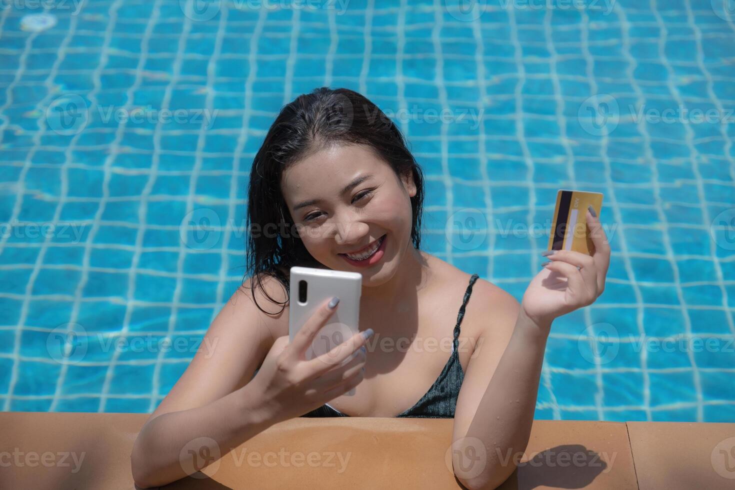 ung kvinna med bikini i slå samman använder sig av smartphone och innehav kreditera kort för handla uppkopplad. överallt uppkopplad handla begrepp. foto