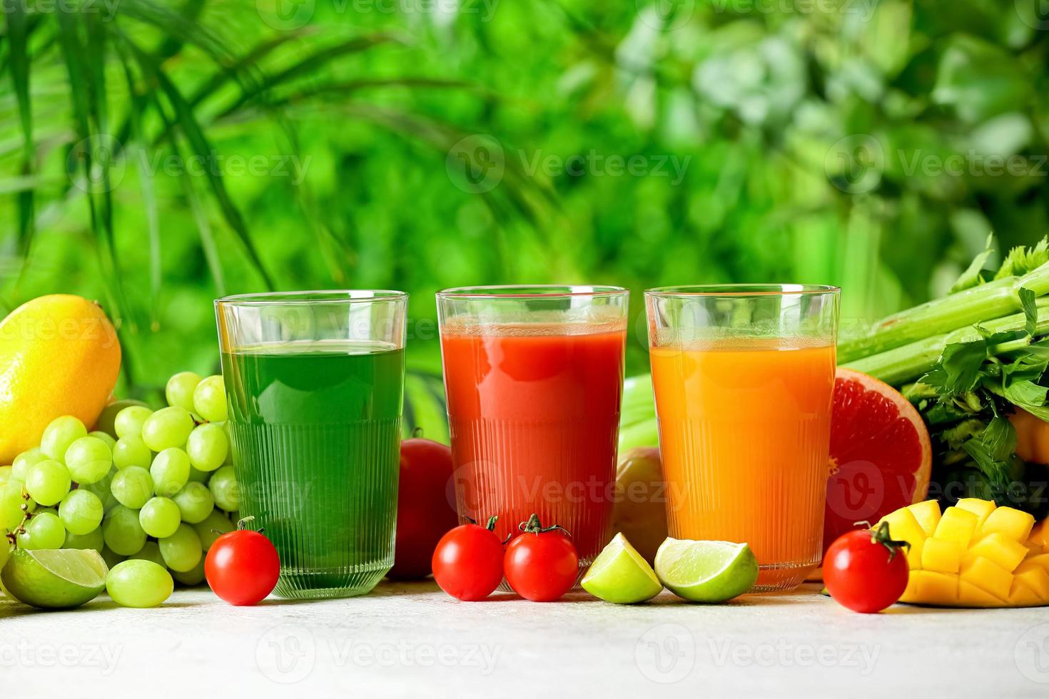 glasögon med hälsosam juice, frukt och grönsaker på bordet utomhus, närbild foto