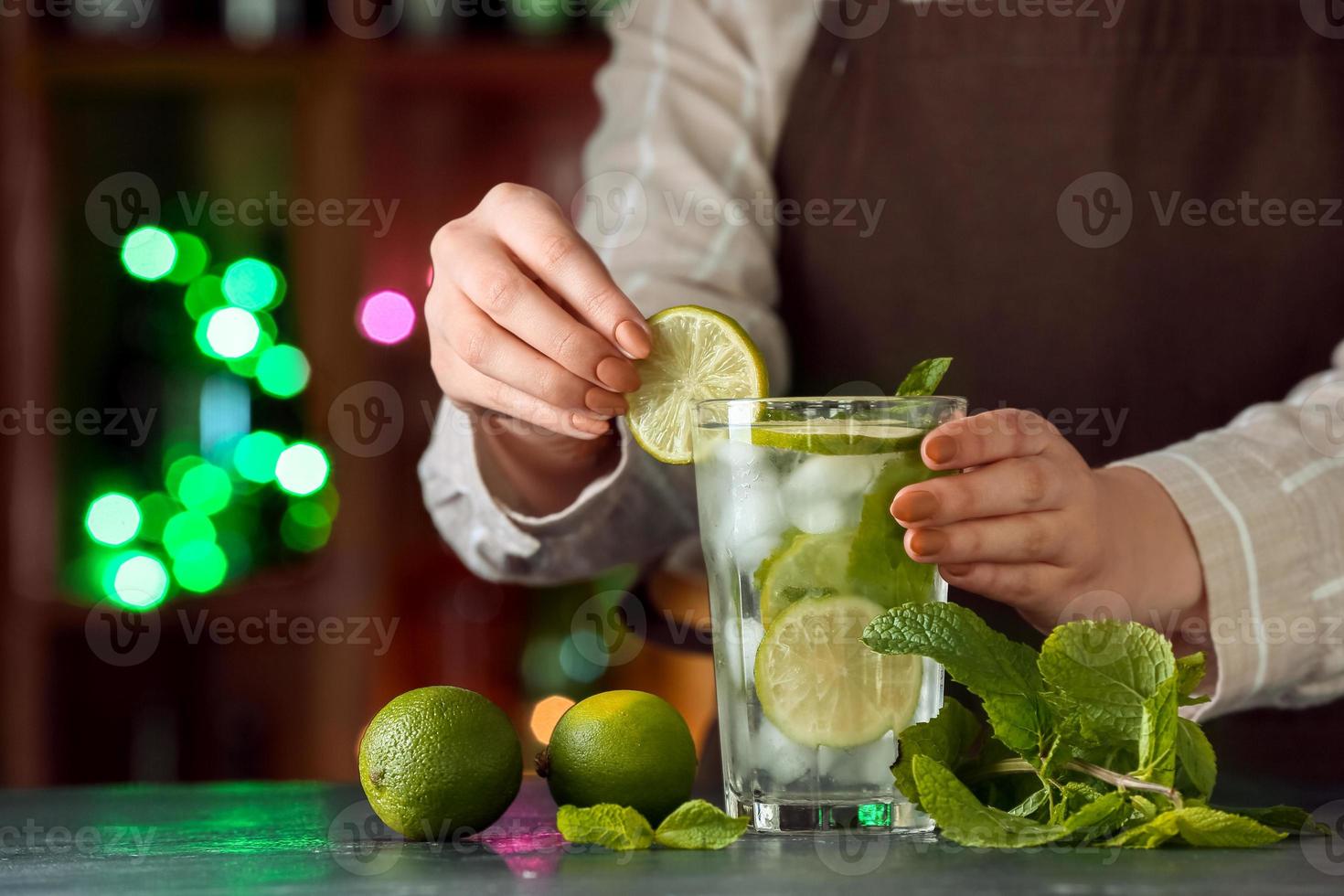 kvinnlig bartender som gör färsk mojito på bordet i baren foto