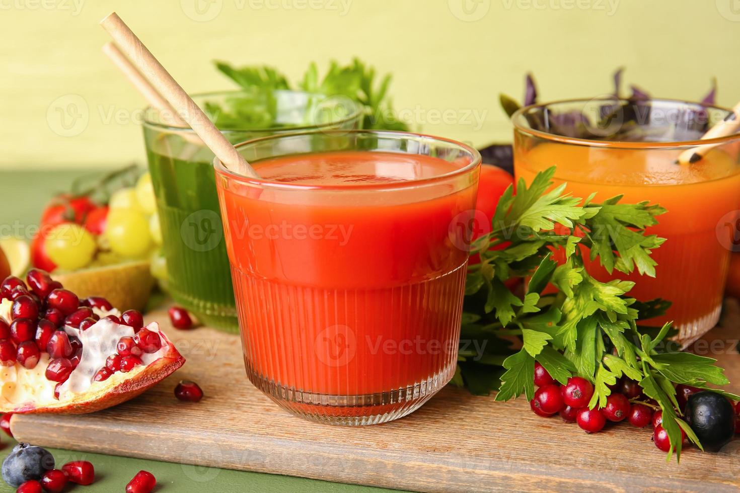 glasögon med hälsosam juice, frukt och grönsaker på färg trä bakgrund foto