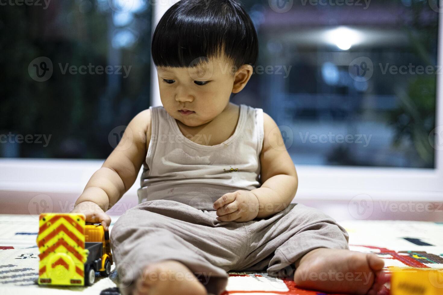 liten pojke spelar med leksak bil i de hus. foto