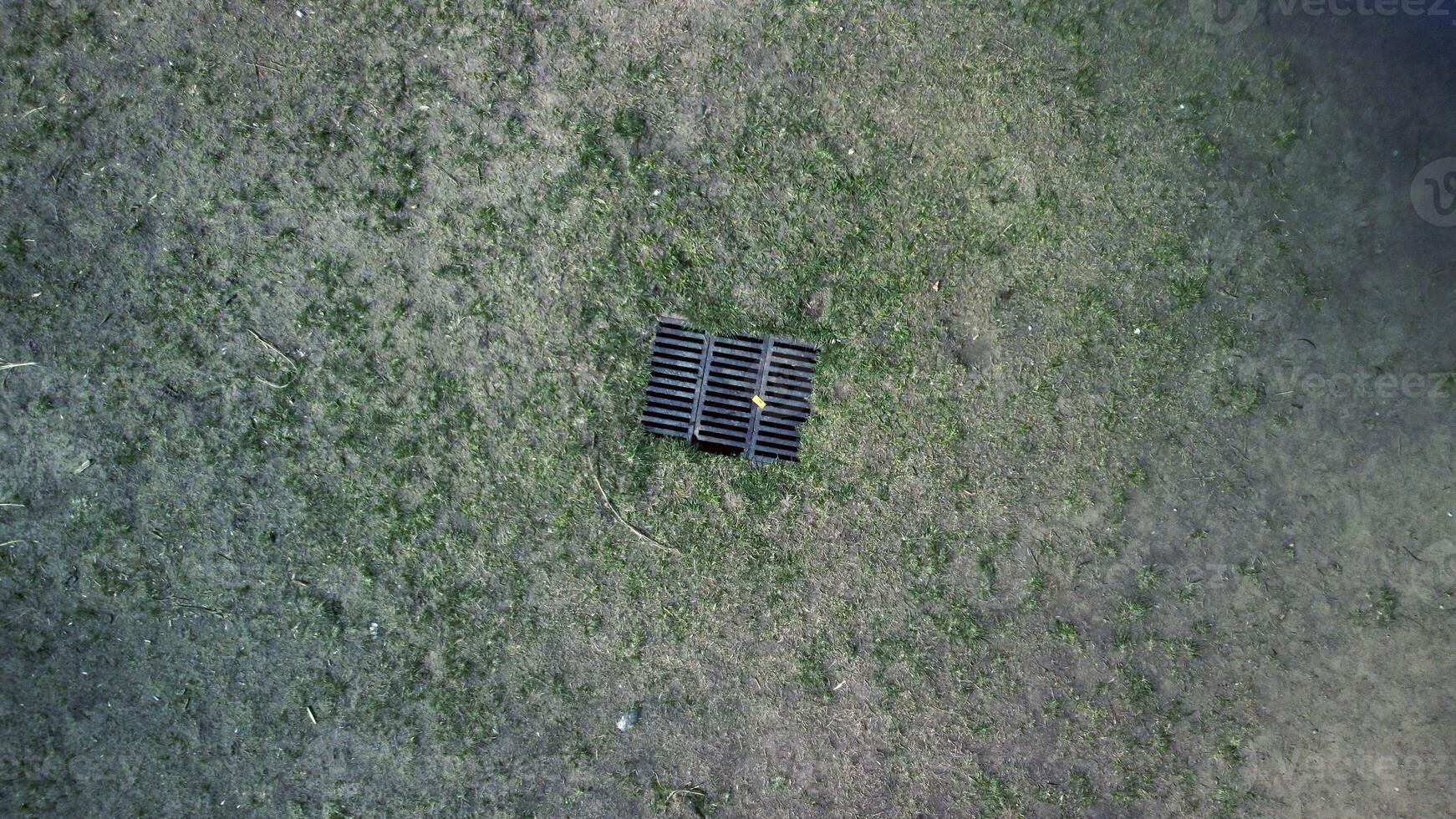 antenn Drönare se på torr gräs och järn metall dränera avlopp rutnät i jorden. foto