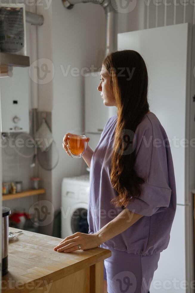 kvinna som tittar ut genom köksfönstret foto