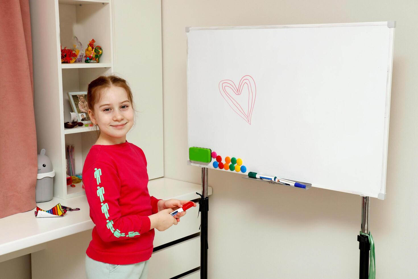 en liten flicka ritade en hjärta på de styrelse med en röd markör, med kopia Plats foto