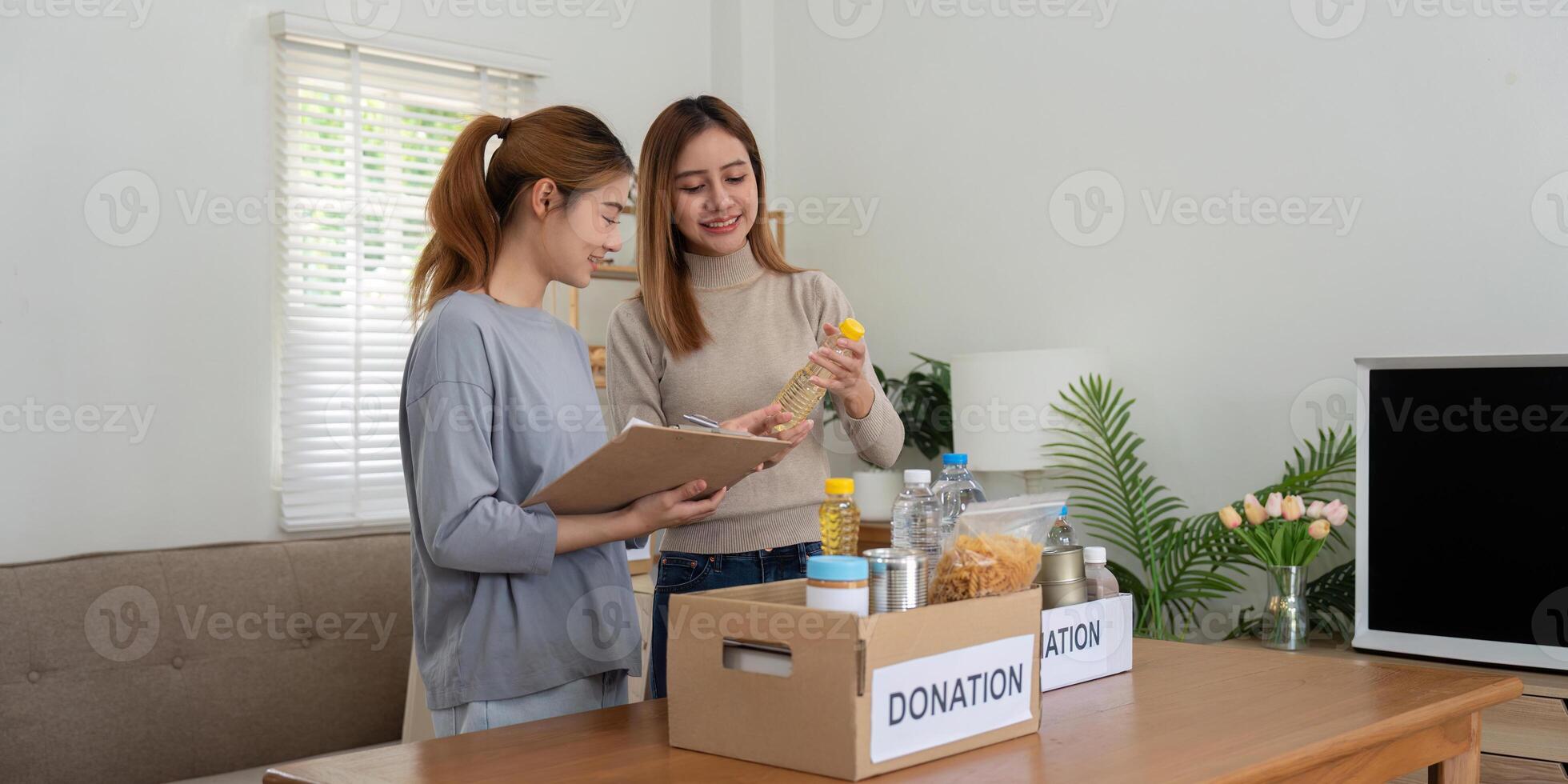 donation och två kvinna volontär- asiatisk av Lycklig förpackning mat i låda på Hem. välgörenhet foto