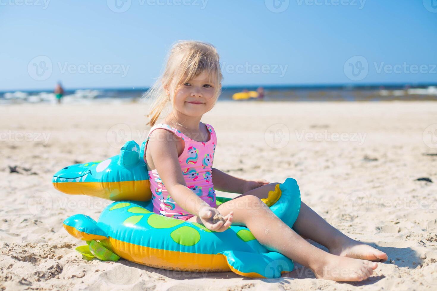 Lycklig flicka av europeisk utseende ålder av 5 Sammanträde på ett uppblåsbar krokodil leksak på de strand sommar solig dag, ser till de kamera.familj sommar yrke begrepp. kopia Plats. foto