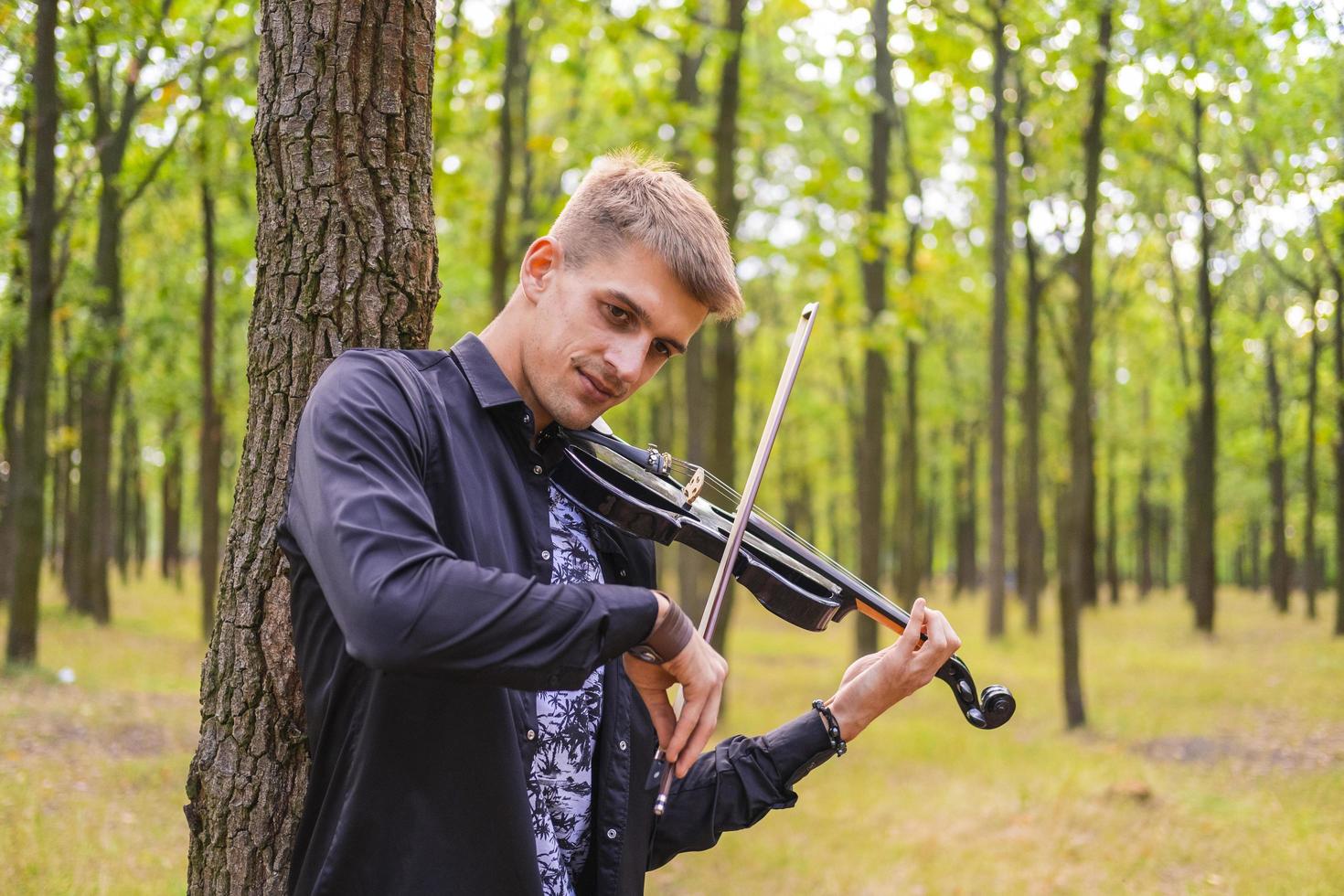 ung man spelar på fiol i sommarparken foto