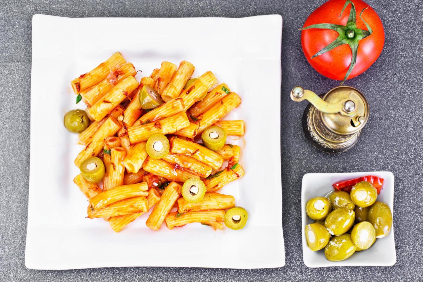 tortellini, pasna penne med ketchup och gröna oliver foto