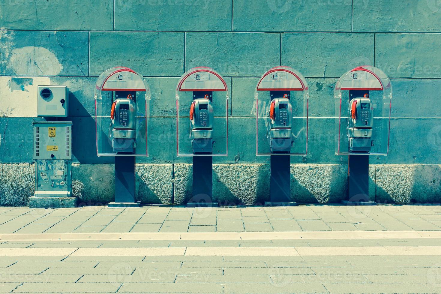 fyra telefonkiosker vid väggen. Trieste, Italien foto