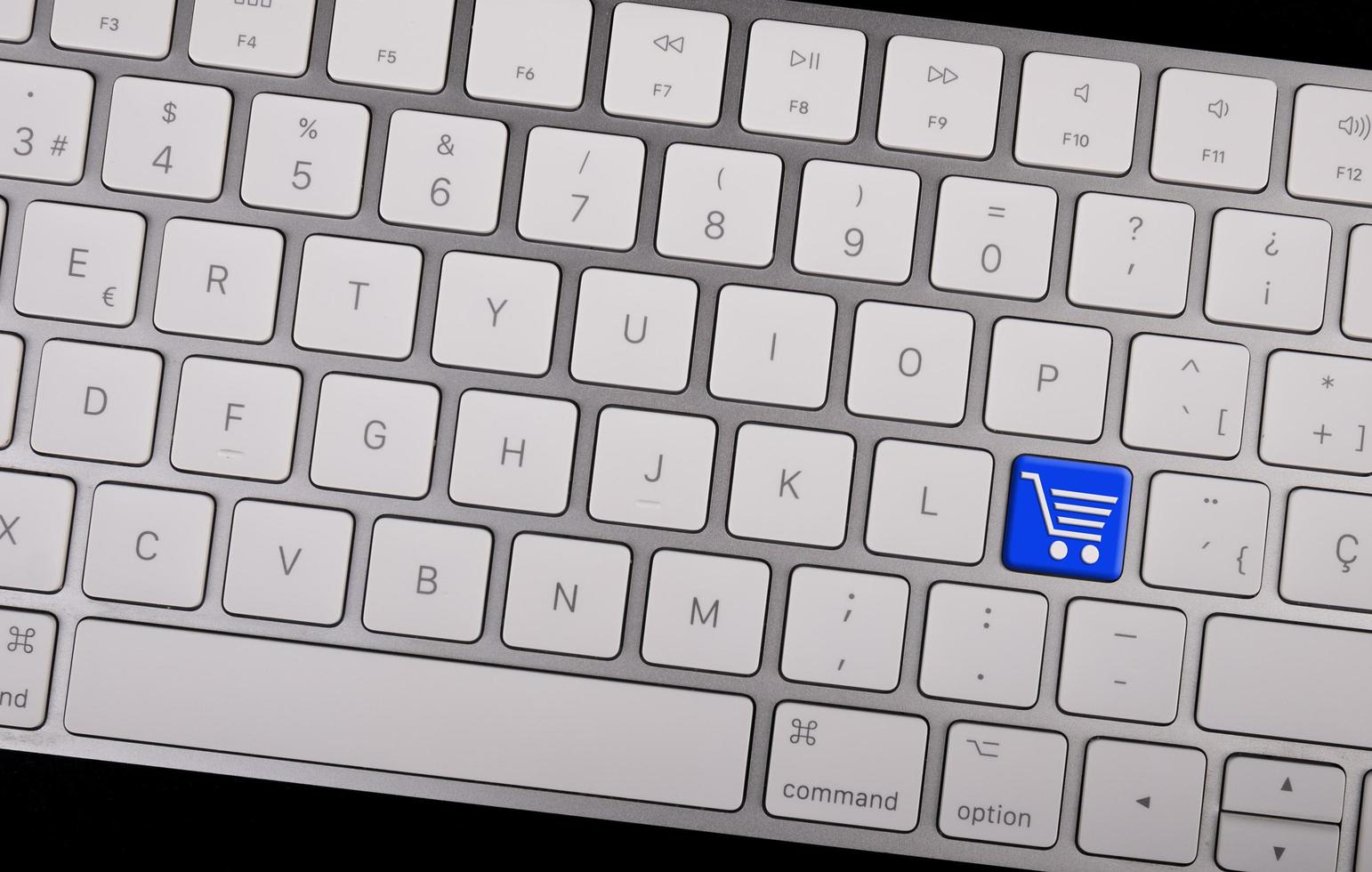 dator anteckningsbok tangentbord med ikon kundvagn på nyckel. e-handel koncept foto