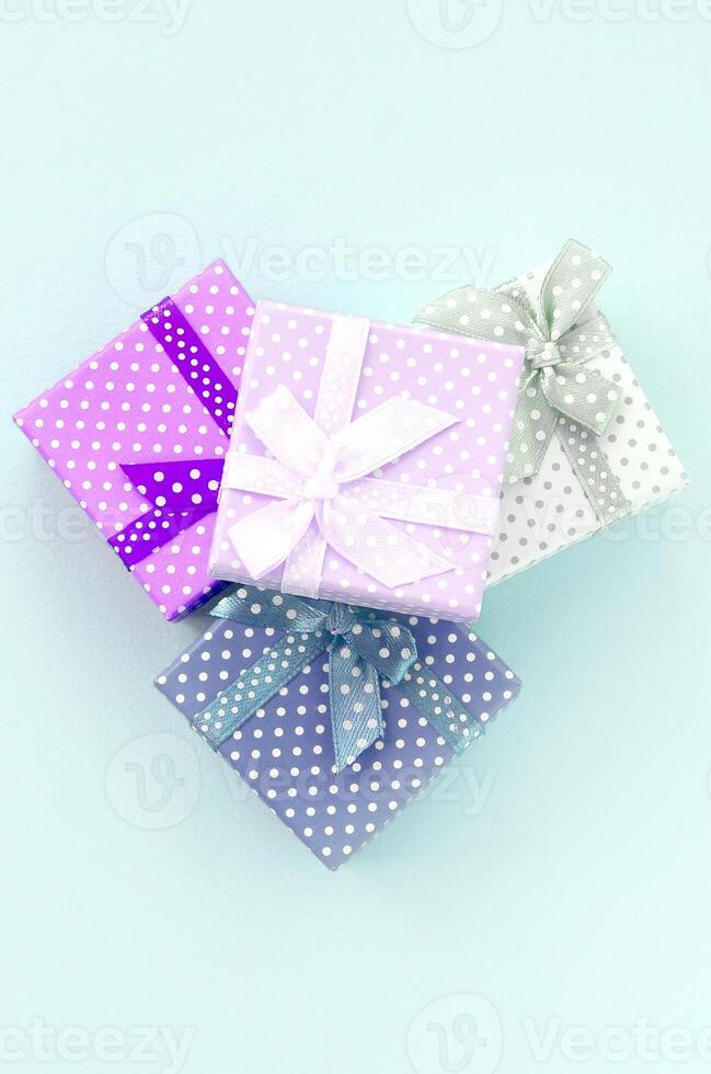 lugg av en små färgad gåva lådor med band lögner på en violett bakgrund. minimalism platt lägga topp se foto