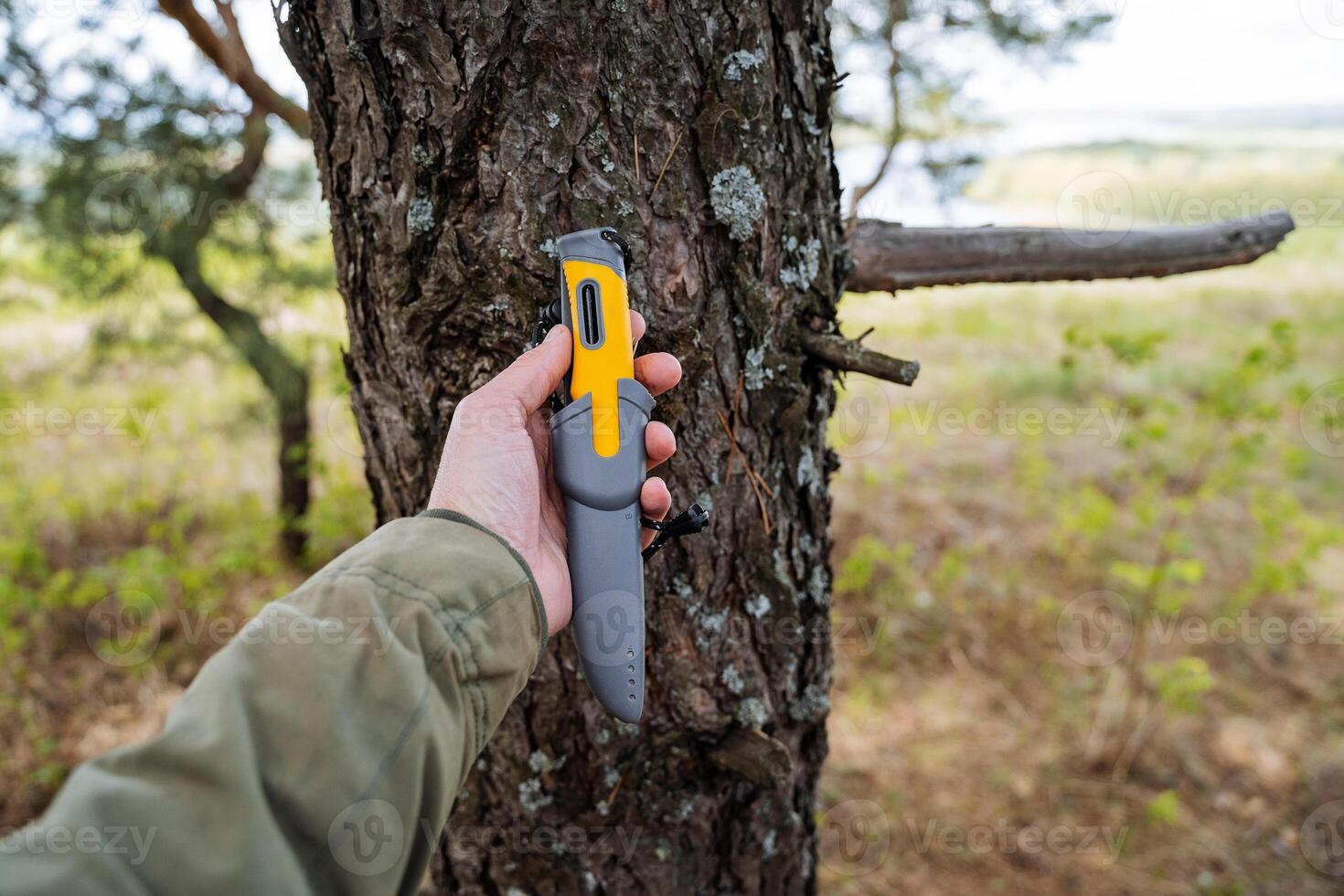 camping Utrustning är en kniv för överlevnad i de skog, en mannens hand innehar en grå kniv i en slida. foto