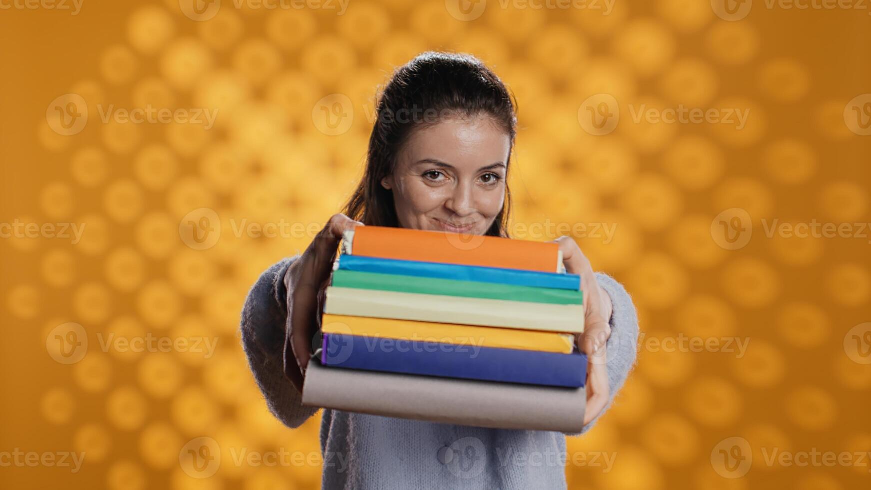 porträtt av vänlig kvinna erbjudande stack av läroböcker användbar för skola examen, isolerat över studio bakgrund. glad person ger lugg av böcker, rekommenderar dem för universitet bedömning, kamera b foto