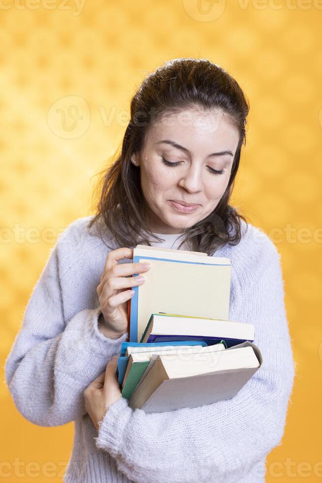 porträtt av glad kvinna bläddring genom stack av böcker, sammankomst information för skola examen, studio bakgrund. strålnings studerande rodra genom läroböcker lugg, framställning för kurser foto