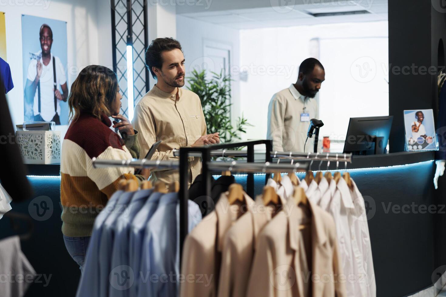 man assistent portion kvinna välja kläder i handla köpcenter mode boutique. Kläder Lagra arbetstagare kund be arbetstagare för råd medan väljer utrusta i utställningslokal foto