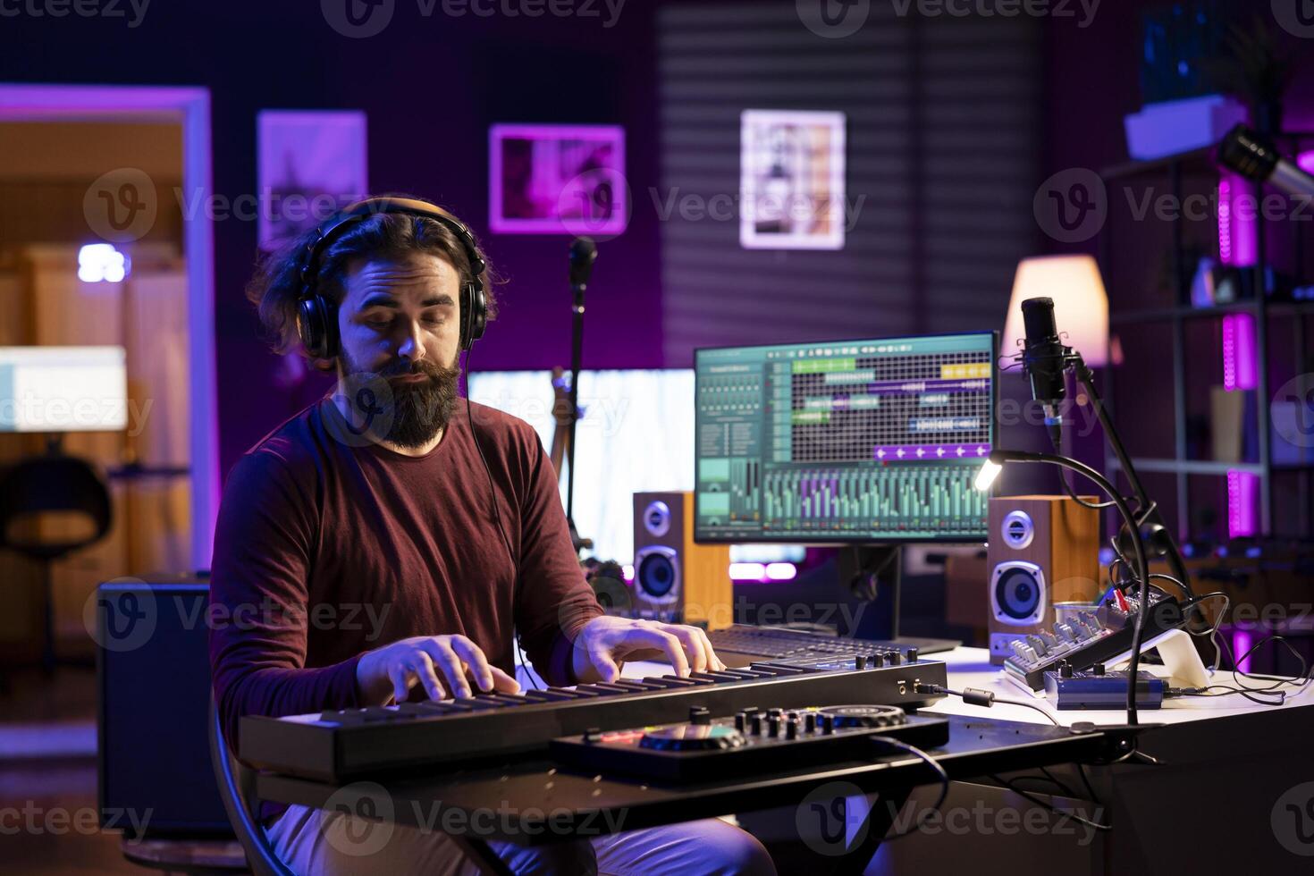 konstnär spelar piano midi kontrollant och inspelning ny låtar, producerar ny elektronisk anteckningar i hans Hem studio. ljud ingenjör arbetssätt på digital audio arbetsstation gränssnitt, synthesizer nycklar. foto