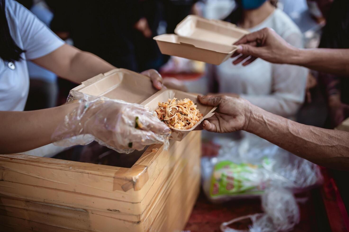 de hand av de vandrare sträcker sig till motta mat från donationer. med volontärer ösa mat. de aning av portion med hunger foto