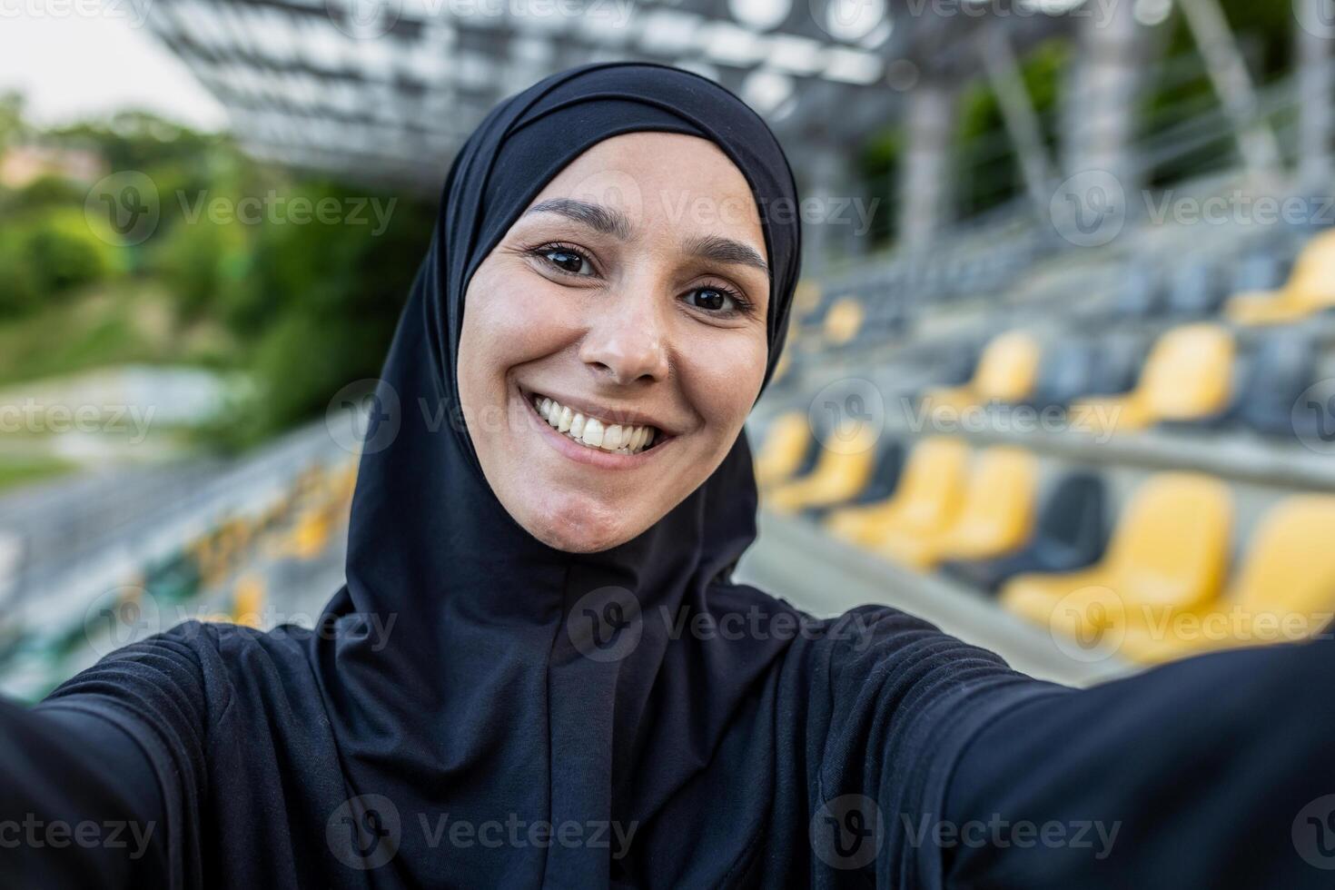 en självsäker idrottare på de sporter stadion fångar en ögonblick av ensamhet med en selfie bär en svart luvtröja. foto