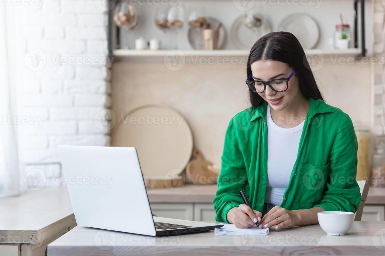 en ung kvinna journalist, författare, bloggare Arbetar avlägset från Hem använder sig av en bärbar dator uppkopplad och anteckningar foto