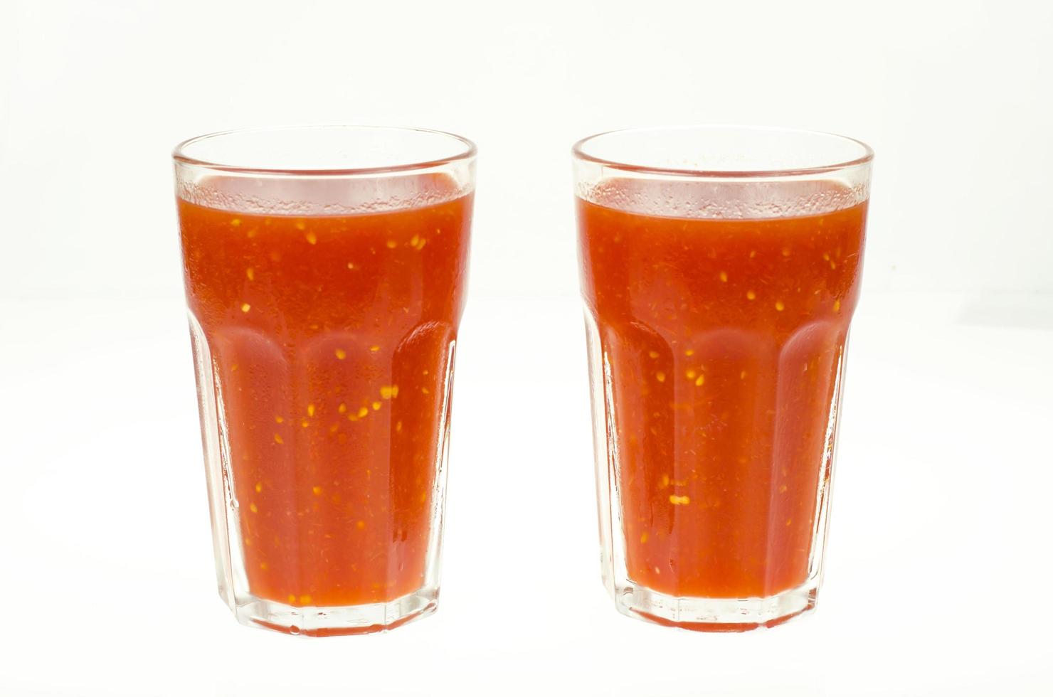 naturlig tomatjuice i glas på vit bakgrund. foto