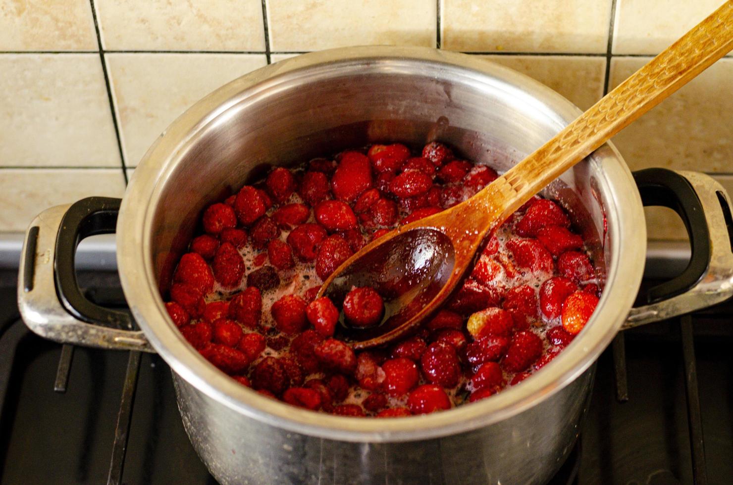 jordgubbar kokas med socker i pannan. foto