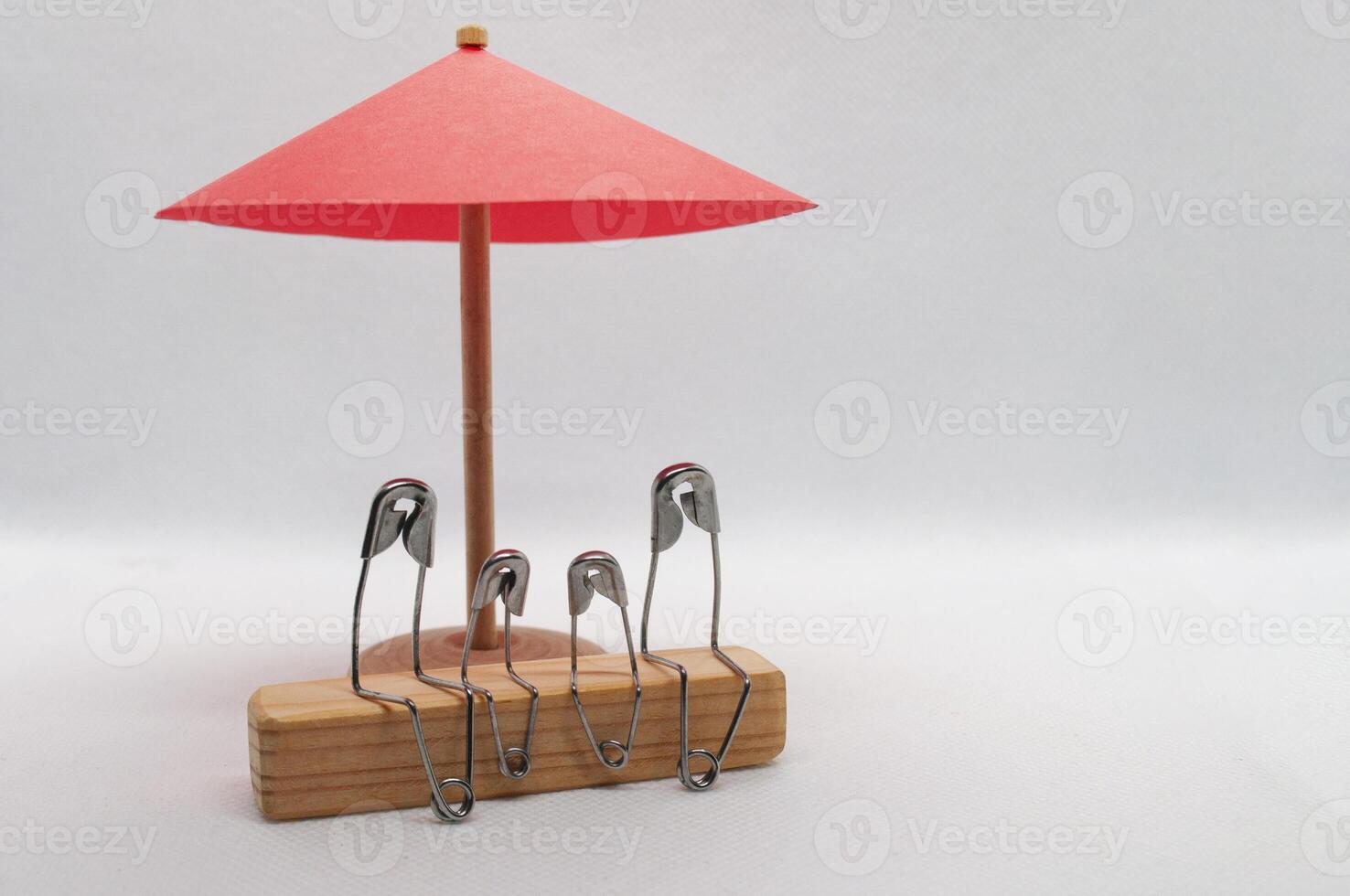 modell säkerhet stift av familj Sammanträde på trä- blockera med röd paraply bakgrund. familj försäkring begrepp foto
